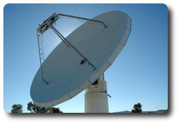 Sun behind white metal dish antenna with black spots