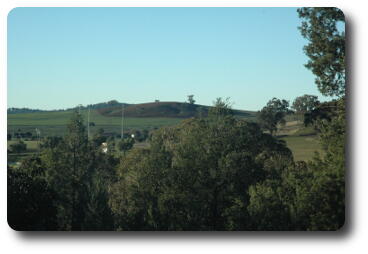 Green fields surrounding brown, ploughed hill