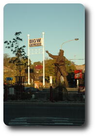 Statue with arm pointing to shop sign