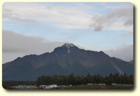 Rugged mountain, dusting of snow on top, viewed across river