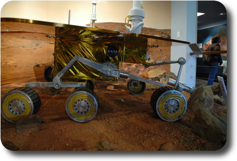 Mars rover in display of simulated surface of Mars; side on view