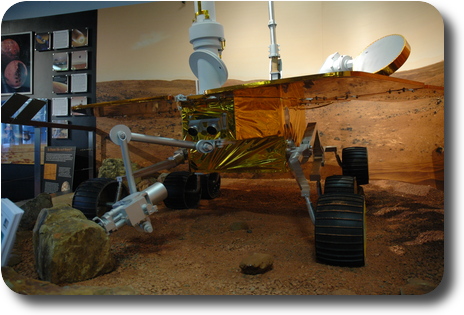 Mars rover in display of simulated surface of Mars; front view from ground level