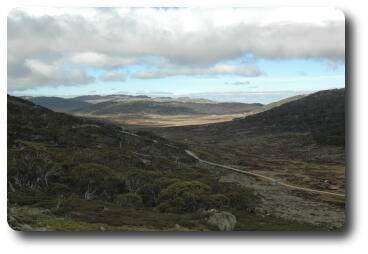 Shallow valley with dirt road, distant mountains