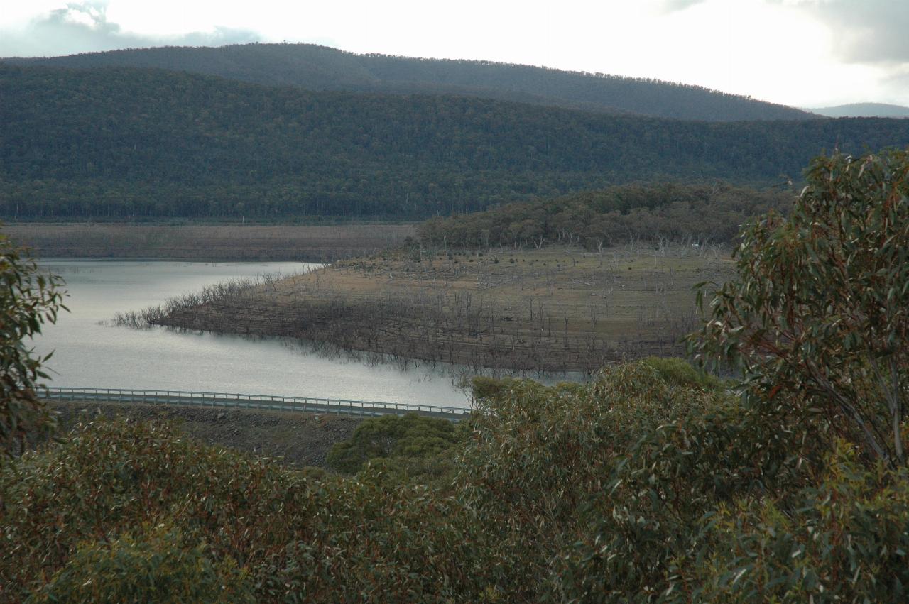 View over dam wall into lake, with low water level and bare shores