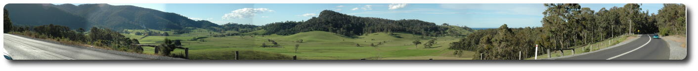 Panorama from mountains, over green pasture to ocean