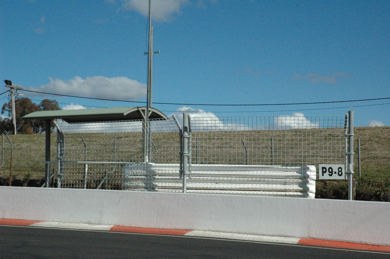 Cement barrier, wire fence around stand with a roof for shade