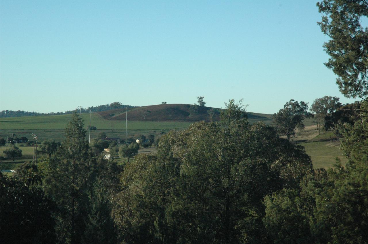 Green fields surrounding brown, ploughed hill