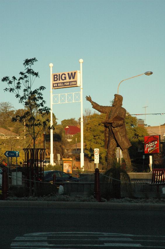 Statue with arm pointing to shop sign
