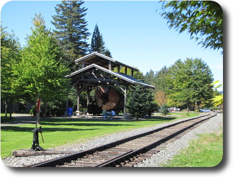Another view of log sitting under shed, with picnicers in front