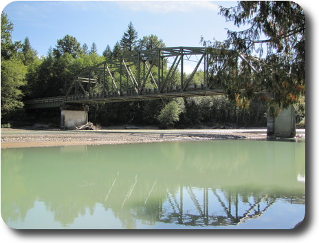 Metal bridge carrying road over river with very little water in it