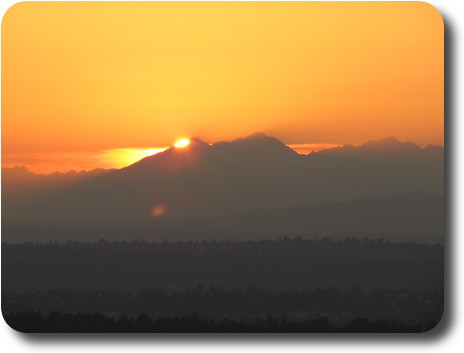 Sun setting behind distant mountains
