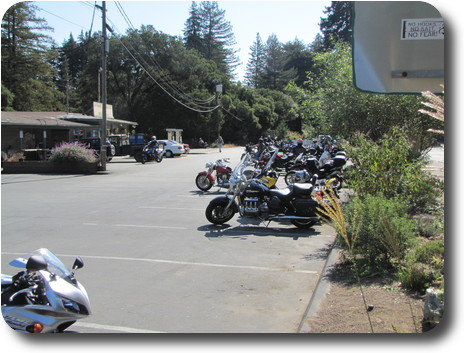 Few motorcycles in front of convenience store amidst trees