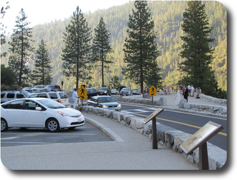 Parking lot with tourists and pine covered mountain to rear