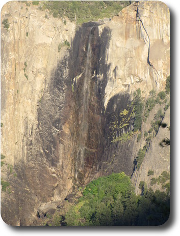 Very thin waterfall on rock face, with trees at the base