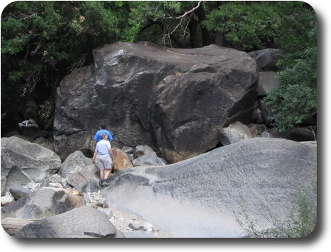 Two people dwarfed by a big rock at least 3 times their height