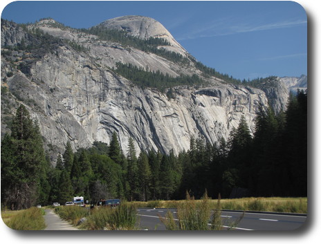 Rock face with arched shapes in the rock, with a large rock dome behind
