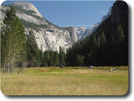 Grassy meadow surrounded by sheer cliffs leading into layers of cliffs in the distance