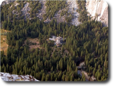 Y shaped building in among trees at the bottom of a cliff