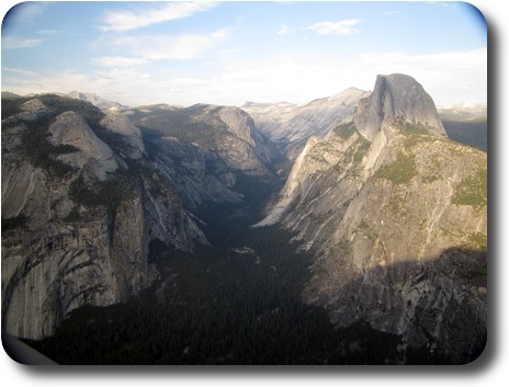 Tree covered valley floor extending into the distance, with gray cliffs on both sides