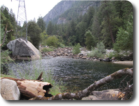 Pool in river in valley; a large boulder on left has electricity pylon on top