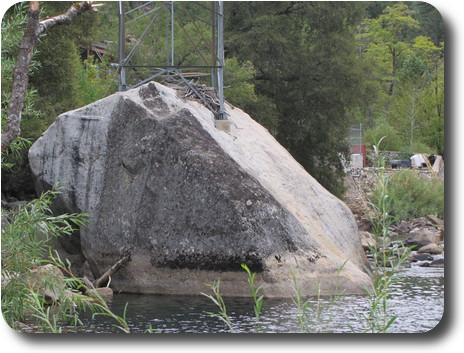 Boulder in pool with electricity pylon on top, and debris caught in pylon