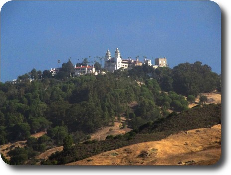 Castle like building, and a number of others, on a tree covered hilltop