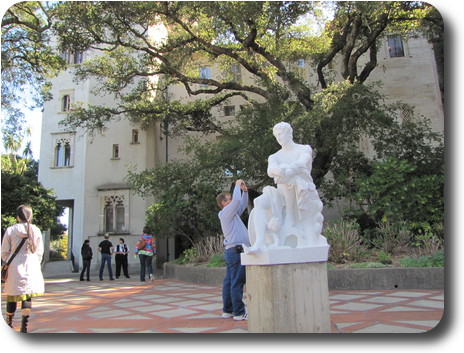 White marble statue on a column in front of four storey building