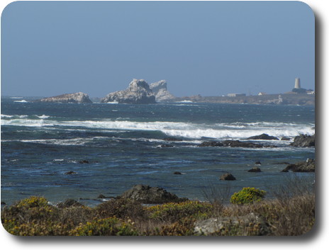 White rocks close to shore and a headland with a lighthouse