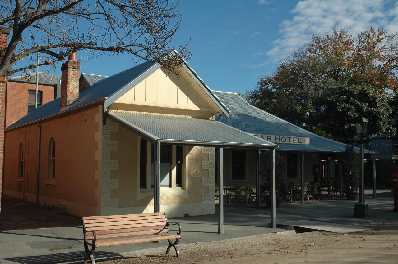 Single level stone building, L shaped, outdoor tables and chairs, grey rood, sandstone walls