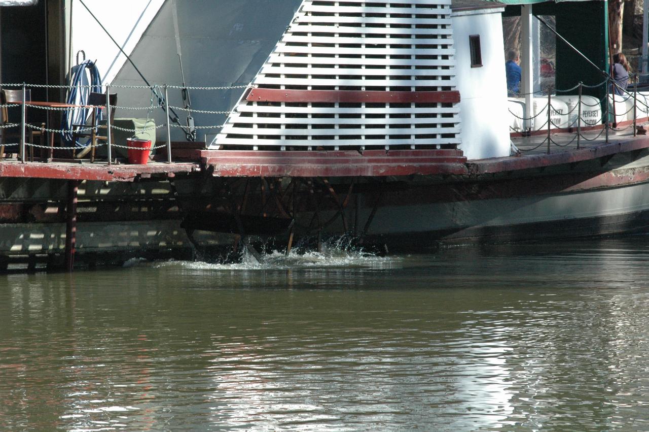 Close up of side of paddle wheeler, with water churned by paddles