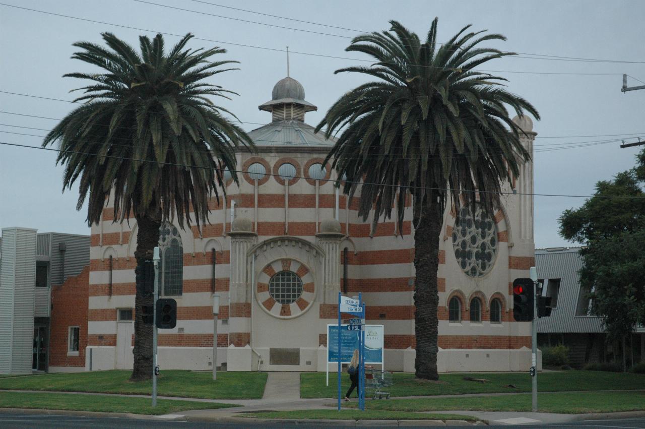 Hexagonal church with orange and gray horizontal stripes, plus a pair of large palm trees