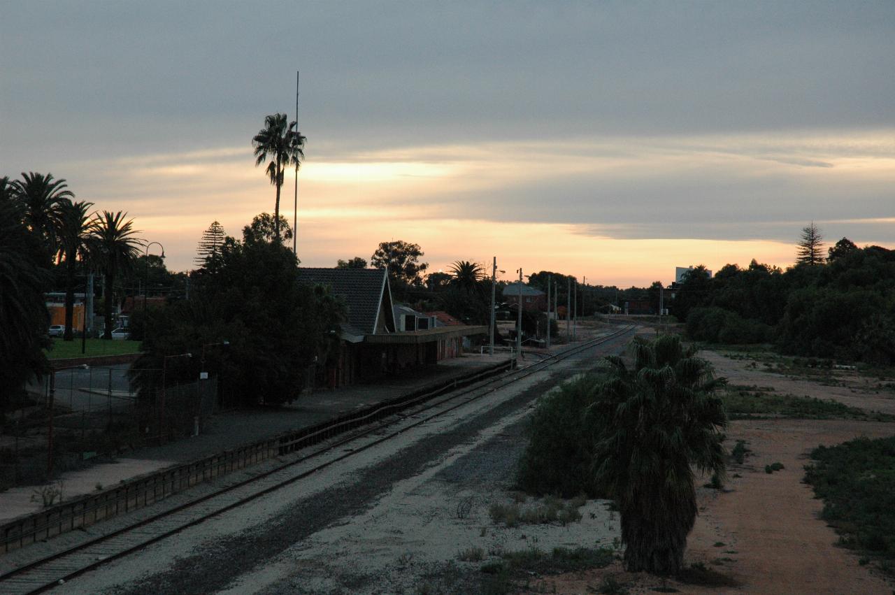 Platform with station building, rail line heading off in distance, gardens behind, viewed from bridge over tracks