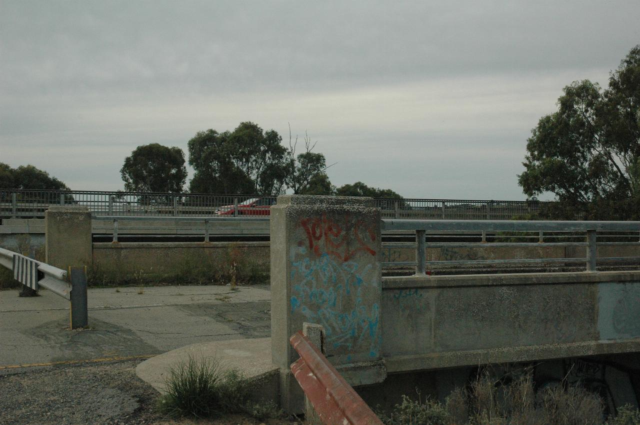 The ends of two bridges, with car on the further, newer bridge.