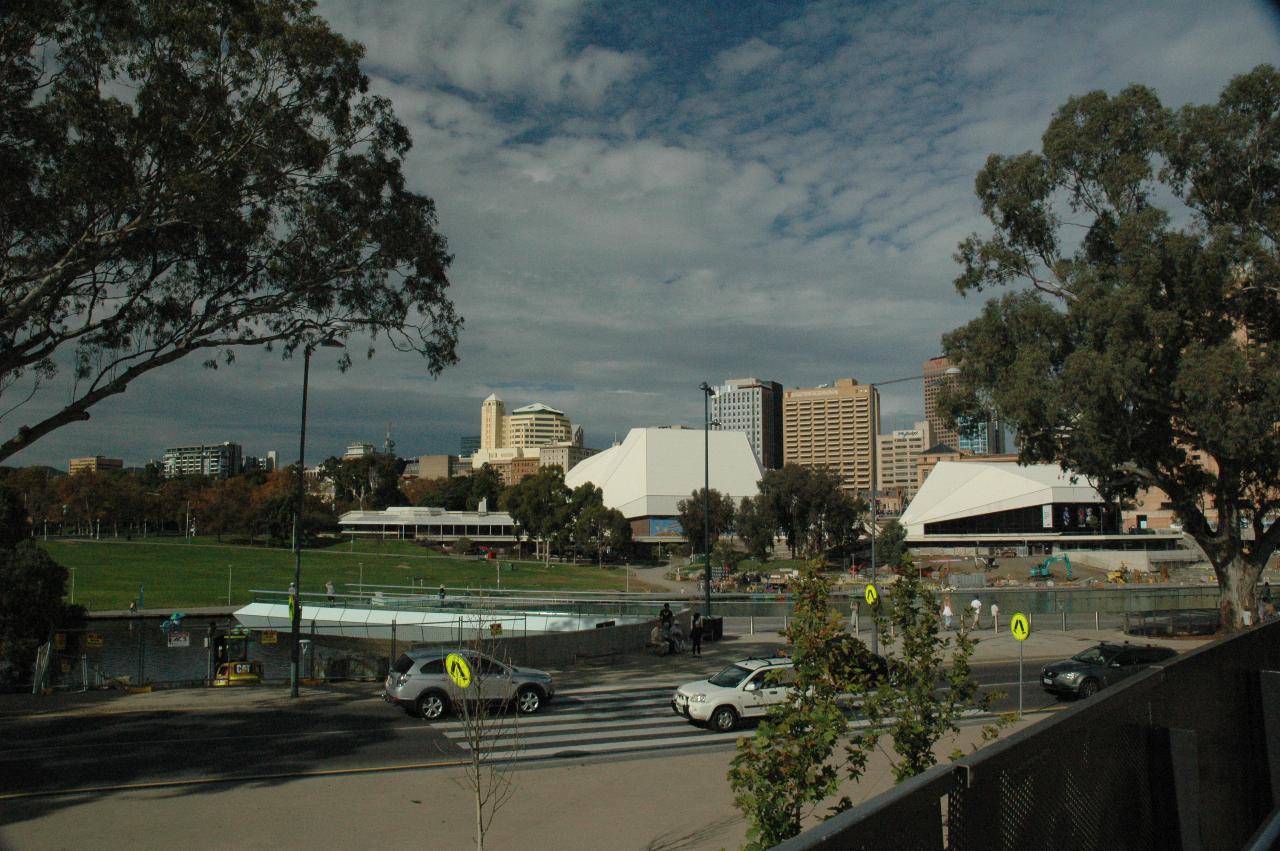 View across river, grassy area to pyramid like white buildings, city buildings behind