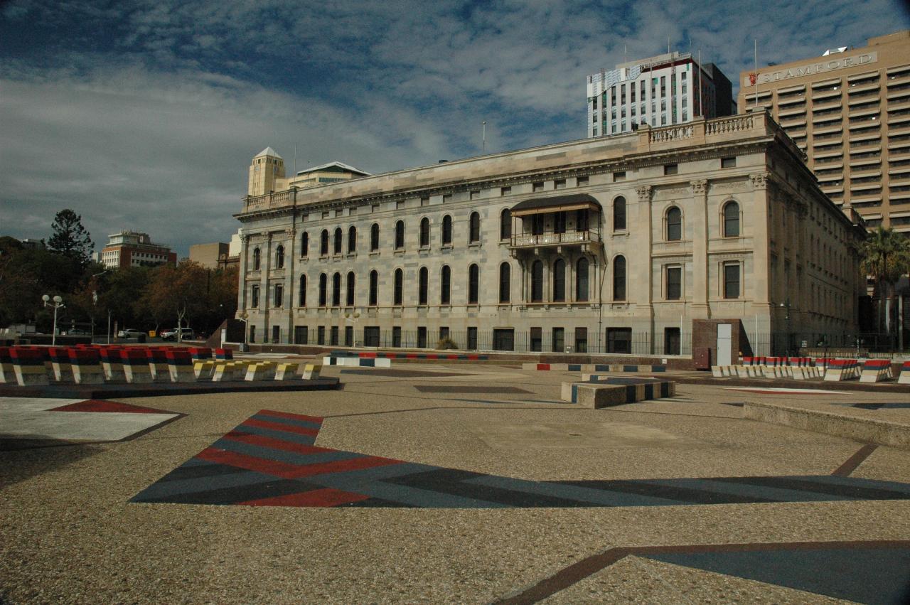 Plain gray building with one small balcony behind plaza area with decorations