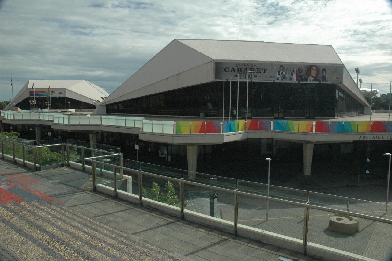 Pair of vaguely pyramid styled buildings, one behind the other, and coloured glass railing in front of nearest