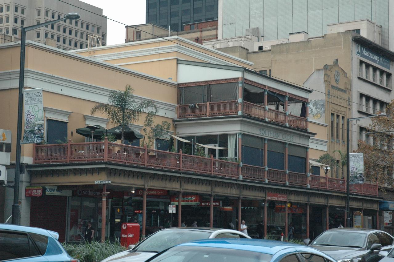 2 and 3 storey tan coloured building with awning over footpath and outdoor restaurant on top of awning