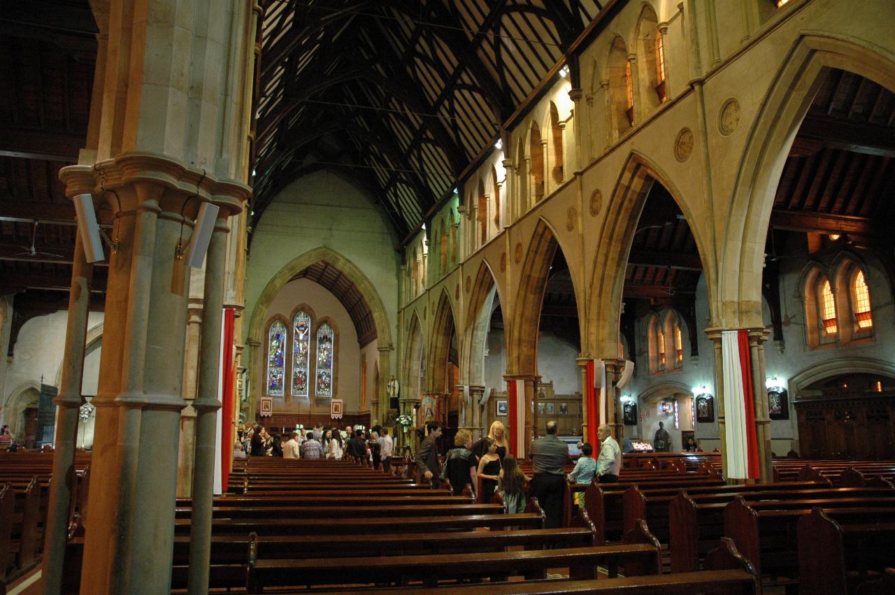 Traditional long corridor church, stone masonary, vaulted ceiling, and some people down near the altar