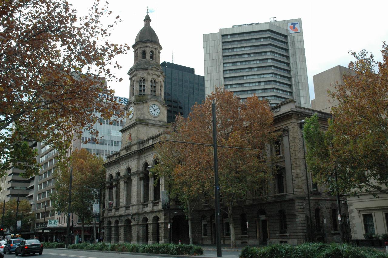 Street scene, with three storey stone building with clock tower in the middle