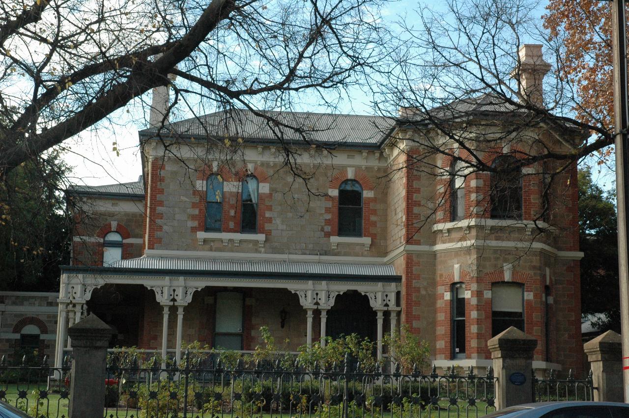 Two storey stone house with red bricks around windows
