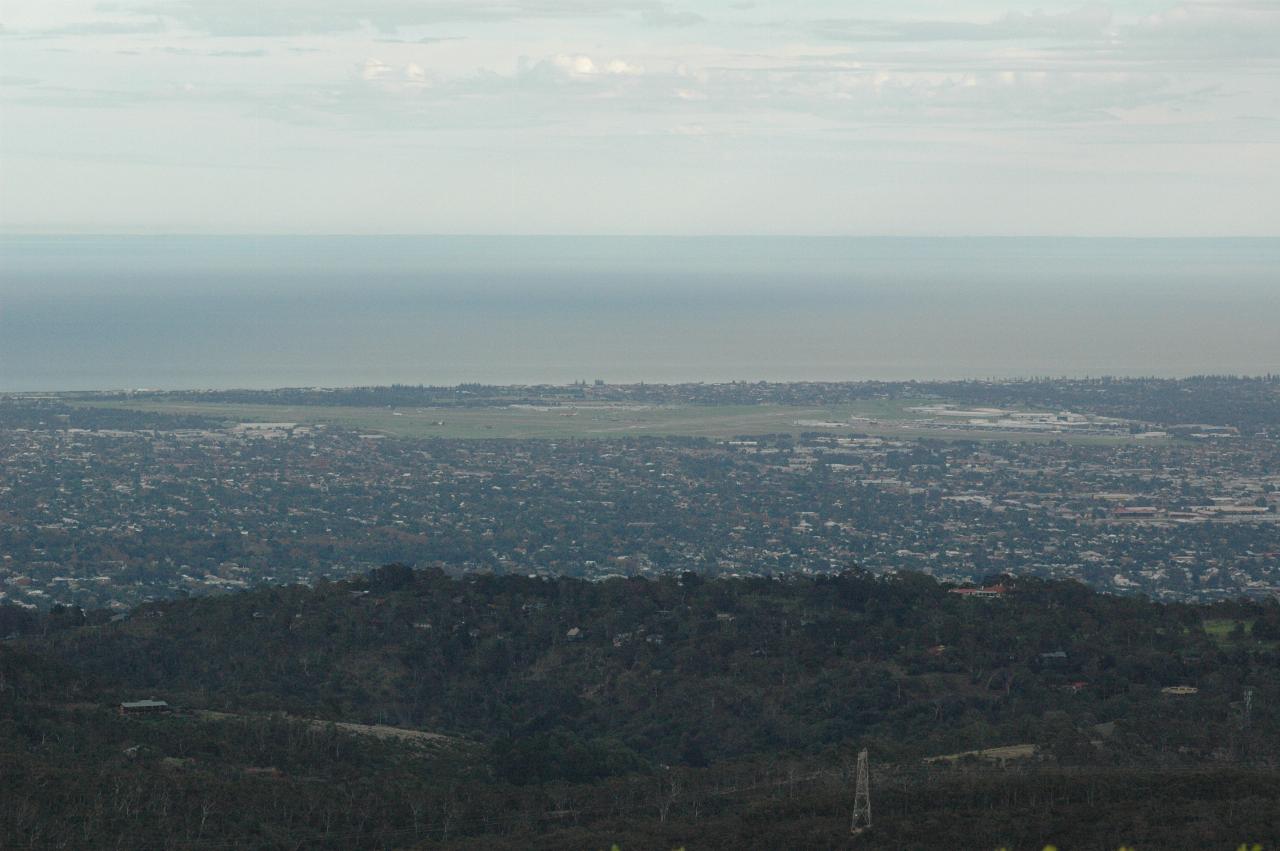 Nearby hill, flat plain behind, large grassy area then water in distance