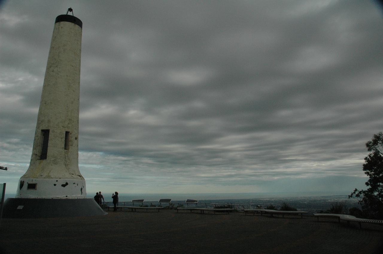 White cylindrical column in flat area, distant water views, grey sky