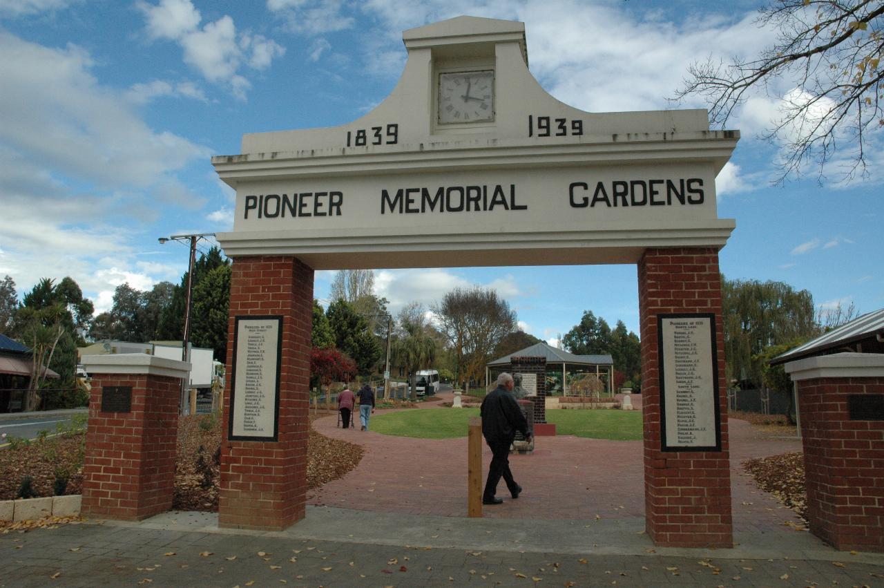 Brick and cement archway into park like area, sign 