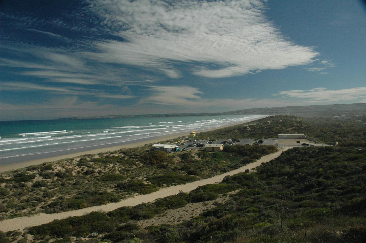 Up high view of beack, waves, car park and lifeguard tower and other facilities
