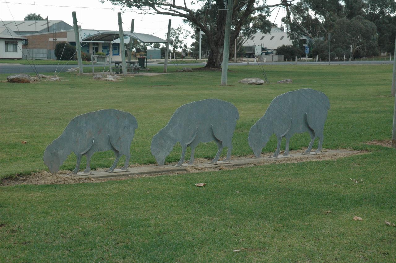 Side on view of 3 metal shapes in a grassy area