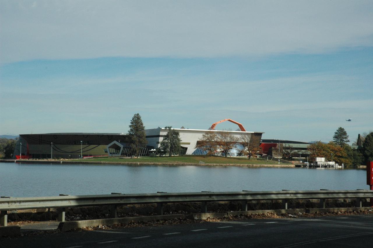 Black and white buildings with red semi-circle above behind part of lake