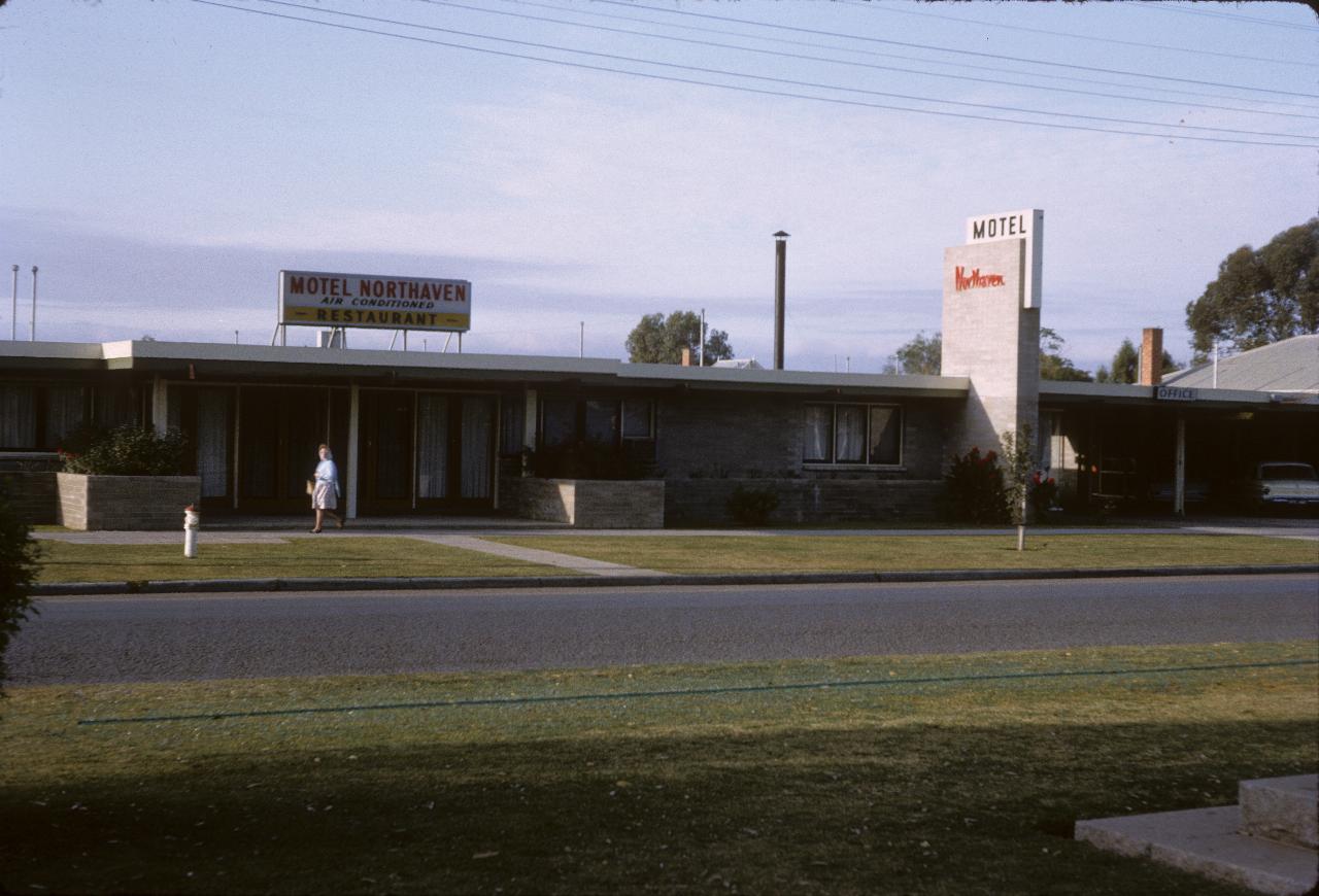 Single story gray brick motel on divided street