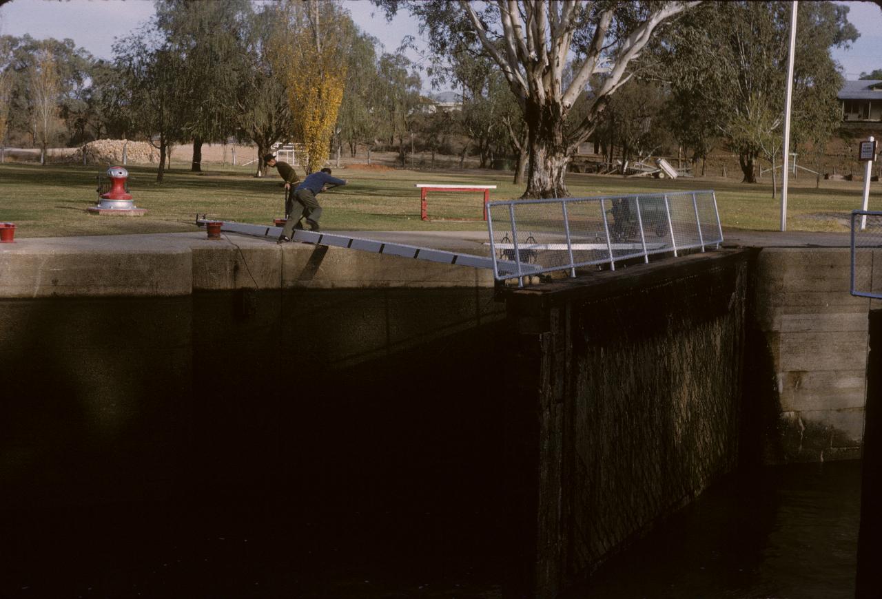 Two men manually closing the lock gate