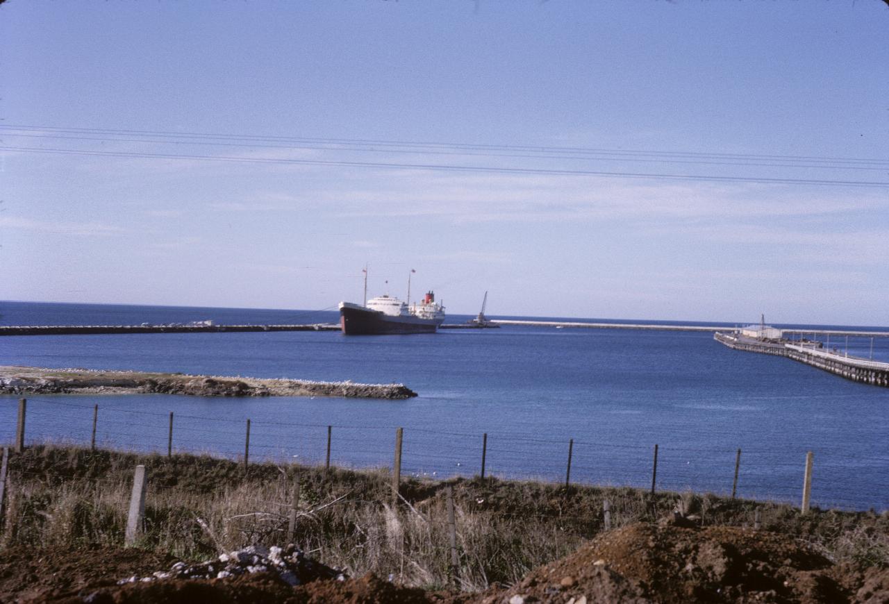 Freighter docked at wharf extending out from the coast