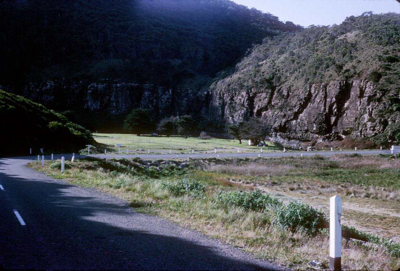 Camp ground below steep cliffs as road makes right turn